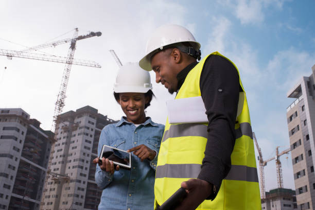 Teamwork on construction site, working at the construction site, using a tablet computer. Couple checking plans on digital tablet.